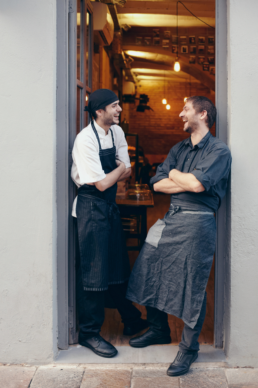 Two cooks laughing together at the door of the coffee shop